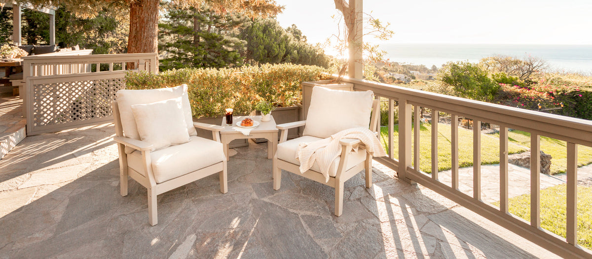 A POLYWOOD Chinoiserie 3 Piece Deep Seating Set in Sand with Natural Linen cushions sits on a stone balcony.