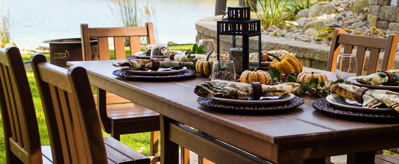 Fall decor and place settings sit on a brown POLYWOOD Traditional Garden 7 Piece Farmhouse Dining Set With Trestle Legs.