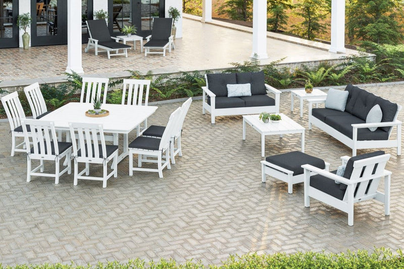 A mix of white POLYWOOD deep seating patio furniture and traditional dining and lounge sets sits on a brick patio and porch.
