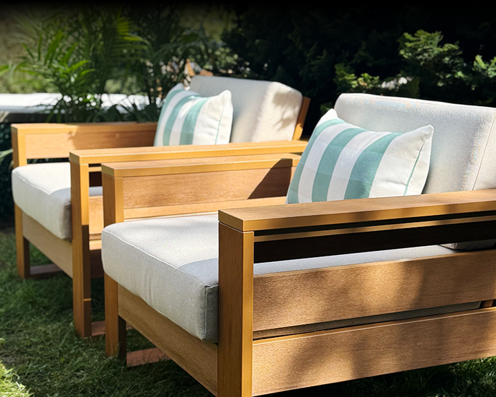 POLYWOOD deep seating chairs from the Latitude Collection with white cushions and striped pillows sit on a grassy lawn. 