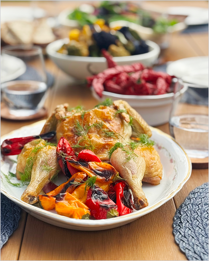 A roasted chicken with colorful peppers is served on a brown POLYWOOD outdoor dining table.
